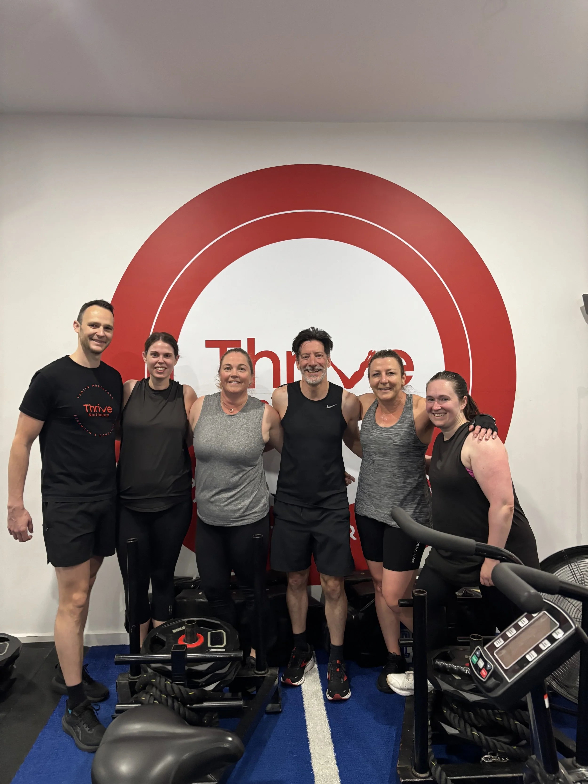 Coaches and members of Thrive Northcote standing in front of the studio logo